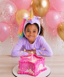 Child wearing a lavender unicorn costume with a golden horn and pastel rainbow mane