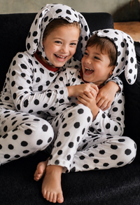 Two children wearing matching Dalmatian costumes with floppy puppy ears