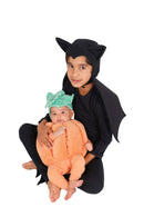 Adult in a black bat costume holding a baby dressed in an orange pumpkin costume
