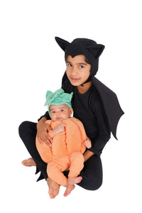 Adult in a black bat costume holding a baby dressed in an orange pumpkin costume
