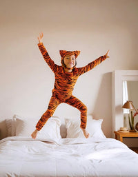 Child jumping while wearing an orange tiger Halloween costume with ears and tail